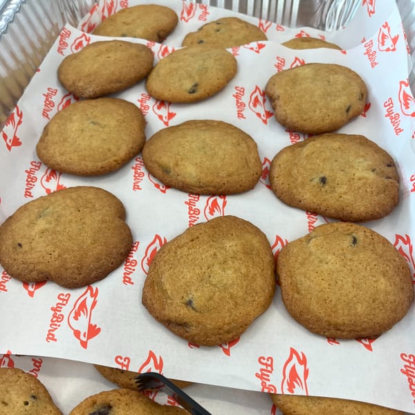 A tray of FlyBird chocolate chip cookies on branded white and red parchment paper.