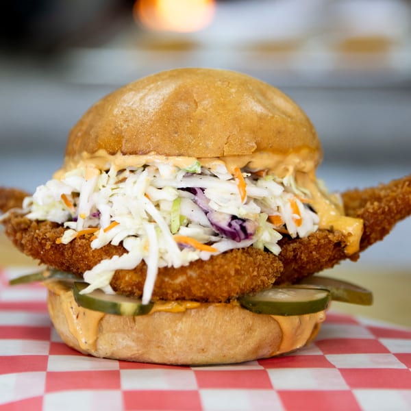 FlyBird's crispy fried chicken sandwich with coleslaw, pickles, and special sauce on a bun.