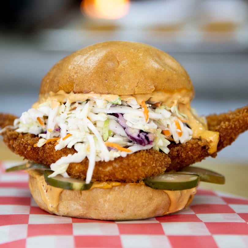 FlyBird's crispy fried chicken sandwich with coleslaw, pickles, and special sauce on a bun.