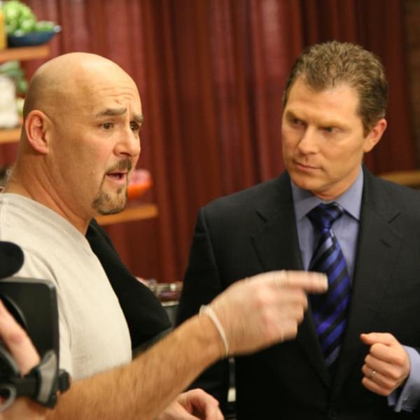 Two men, one bald and one in a suit, conversing with the bald man pointing.